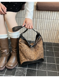 Dettaglio della borsa a secchiello leopardata con manico e finiture in pelle nera premium