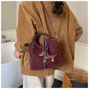 Detail view of burgundy frosted bucket bag with leather dachshund charm and slim strap