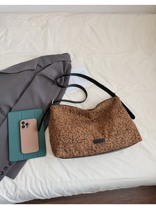 Vue à plat du sac cabas imprimé léopard avec bandoulières en cuir et accessoires lifestyle
