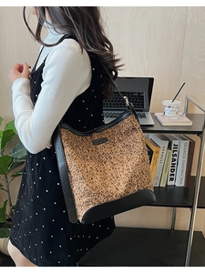 Dettaglio borsa a secchiello leopardata con cinturini in pelle nera in un contesto lifestyle