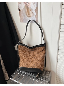 Dettagli della borsa a secchiello leopardata con finiture in pelle su valigia argento