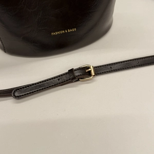 Detail van donkerbruin glanzend leer met goudkleurige opdruk en metalen gesp
