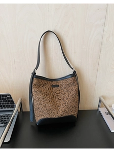 Dettaglio della borsa a secchiello leopardata con rifiniture in pelle sul tavolo