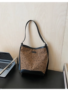 Borsa a secchiello leopardata con cinturini in pelle nera su scrivania con laptop
