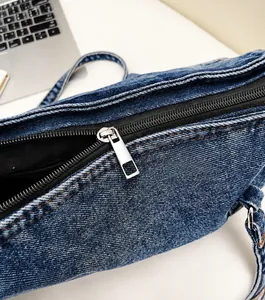 Détail d'une fermeture éclair en métal argenté sur un sac Boston en denim bleu foncé