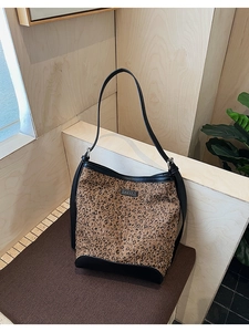 Dettaglio della borsa a secchiello leopardata con finiture in pelle nera su base morbida