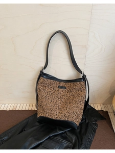Dettaglio della texture leopardata e della tracolla in pelle nera della borsa a secchiello