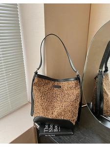 Dettaglio della borsa a secchiello leopardata con paillettes su un libro vicino alla finestra