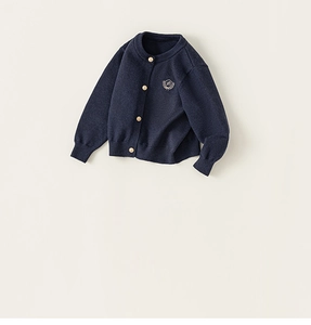 Gros plan du cardigan en maille bleu marine avec boutons dorés et écusson d'école brodé
