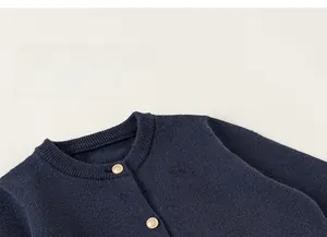 Détail du cardigan en maille bleu marine avec boutons dorés et broderie fine
