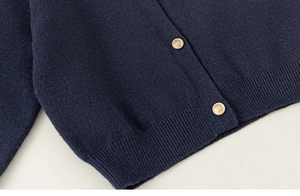 Détail d'un cardigan bleu marine avec ourlet côtelé et boutons dorés gravés