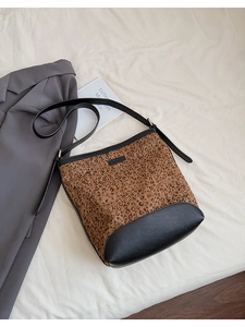 Dettaglio della borsa a secchiello leopardata con cuciture in pelle nera e tracolla regolabile