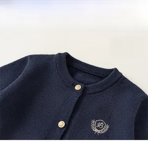 Vue détaillée du cardigan bleu marine avec boutons dorés et blason brodé sur la poitrine