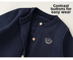 Détail du cardigan en maille bleu marine avec boutons dorés et écusson brodé