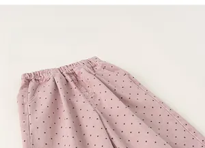 Detail view of pink polka dot trousers showing elastic waistband and fabric texture