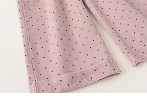 Detail of pink polka dot kids' cotton pants featuring clean stitching on the wide cuff hem