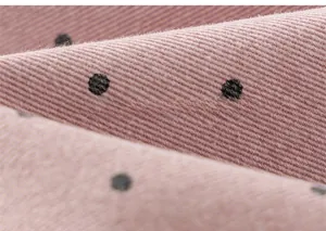 Close-up of pink purple twill cotton fabric with black polka dots for kids trousers
