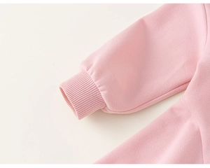 Détail d'une robe rose pour enfant montrant les poignets côtelés et les coutures