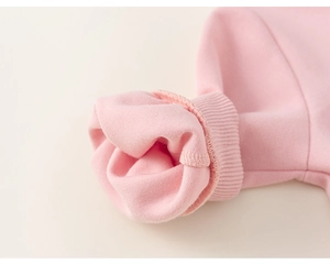 Gros plan des poignets côtelés roses et de la doublure en polaire douce de la robe