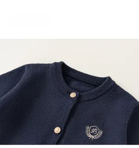 Détails d'un cardigan en maille bleu marine avec boutons dorés et écusson brodé