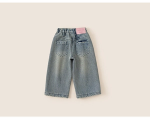 Détail d'un jean large bleu clair pour fille avec taille élastique et écusson en cuir rose