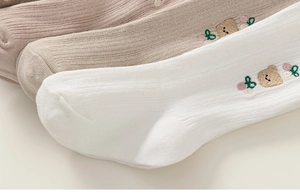 Detailed macro view of cotton baby tights with cute bear and pink flower embroidery