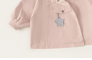 Detail of pink toddler windbreaker featuring ribbed cuffs and silver snap button pocket