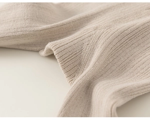 Detail of ribbed knit texture and reinforced flat seams on beige baby leggings