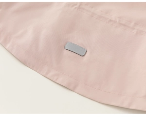 Detail view of pink waterproof fabric with reflective safety strip on kids windbreaker jacket