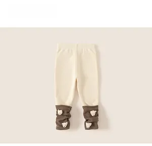 Detail of baby thermal leggings featuring cute 3D plush bear patches and striped knit cuffs