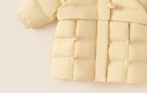 Detailed macro view of square quilting and matte texture on yellow down coat for girls