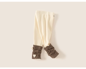 Close-up of baby leggings featuring knit texture and cute plush bear detail on leg cuffs
