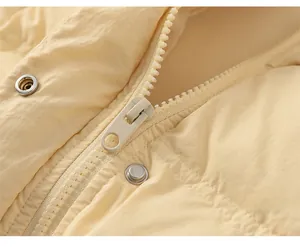 Detail of smooth resin zipper and metal snap button on light yellow down jacket