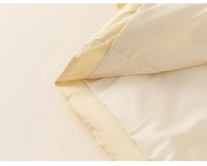 Detail view of cream-colored girl's puffer coat showing fine stitching and fabric texture
