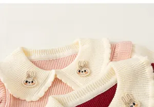 Detail of girls' knitted dress with white scalloped collar and cute rabbit embroidery
