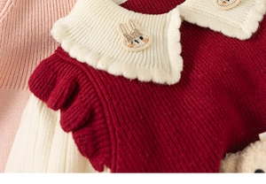 Detailed view of red knitted dress with white ruffled collar and cute rabbit patch detail