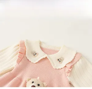 Detail of baby knit dress featuring Peter Pan collar with rabbit embroidery and plush bear
