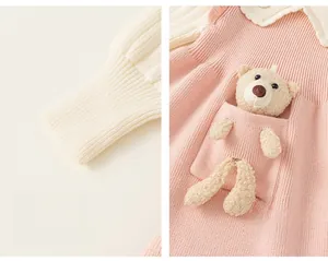 Detail of pink knitted girl's dress showing ribbed cuffs and a cute plush bear in the pocket