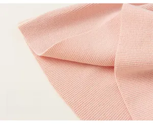 Detail of light pink knitted girl's dress showing ribbed hem and soft fabric texture