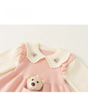 Close-up of pink knit girl's dress with wavy collar and cute 3D plush bear detail