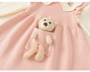 Detail of pink knit dress showing a cute plush bear in the pocket and bunny embroidery
