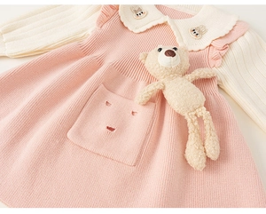 Close-up of pink knit dress featuring a Peter Pan collar, rabbit embroidery and plush bear