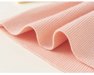 Close-up of pink rib knit fabric showing soft texture and elastic ribbed detail on the dress
