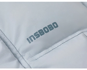 Detailed macro shot of light blue padded winter jacket fabric with logo and stitching