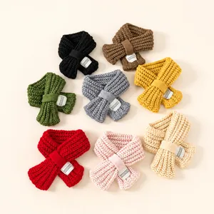 Flat lay of warm knitted crossover scarves in eight solid colors for kids