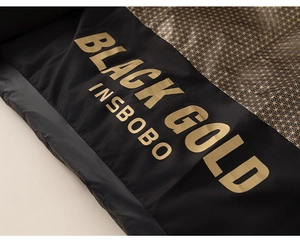 Detailansicht von schwarzem Stoff mit goldenem 'BLACK GOLD' Aufdruck und feinen Sternen