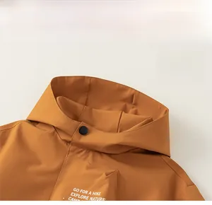Detail of hooded stand-up collar with matte black snap button on mustard yellow jacket