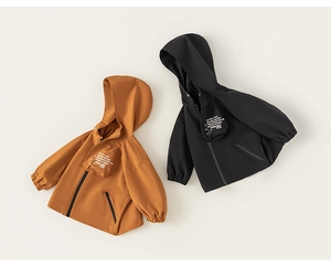 Flat lay of caramel and black hooded windbreaker jackets for kids with outdoor print