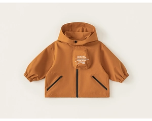 Detail of burnt orange kids windbreaker featuring zip pockets and outdoor explore graphic