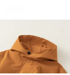 Detail of yellow hooded jacket showing windproof fabric, snap buttons and letter print
